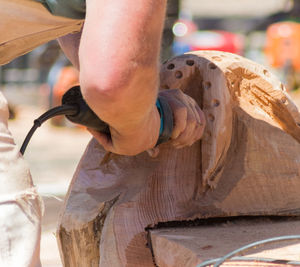 Cropped image of man using drill on wooden sculpture