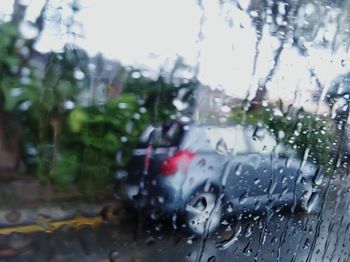 Cars on road seen through wet window during rainy season