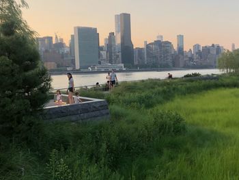 People in park by buildings against sky in city