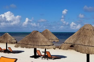 Panoramic view of lounge chairs on beach against sky