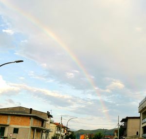 Low angle view of rainbow over buildings against sky