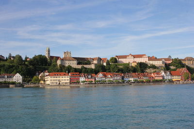 Buildings by river against sky