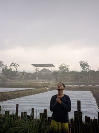 Portrait of young man standing against sky