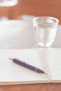 High angle view of pen on book by drinking glass