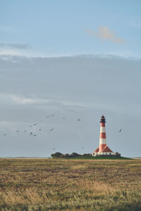 Lighthouse by sea against sky