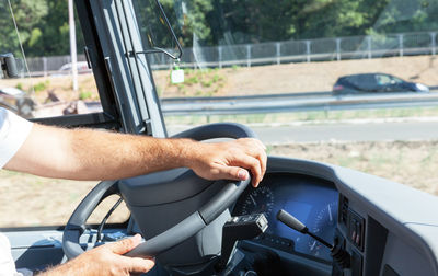 Cropped hands of man driving bus in city