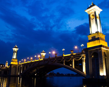 Low angle view of illuminated bridge against cloudy sky at dusk