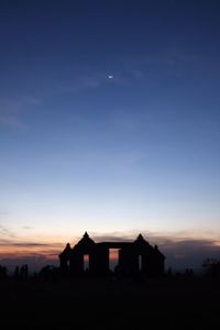 Silhouette house on field against sky during sunset