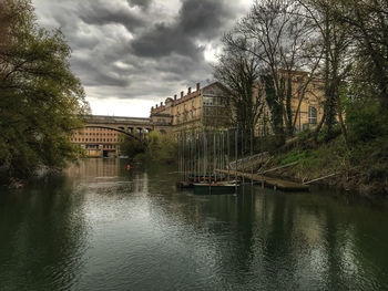 Scenic view of river by buildings against sky