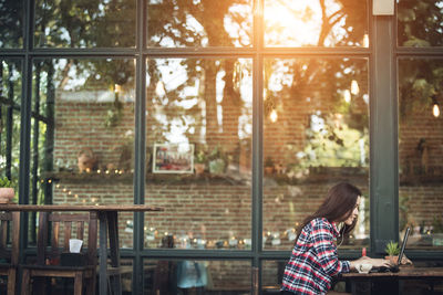 Woman using laptop while sitting on table at sidewalk cafe