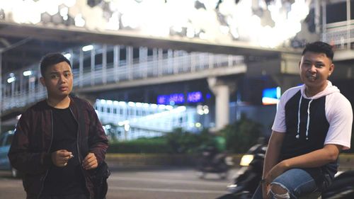 Portrait of young man standing in city at night