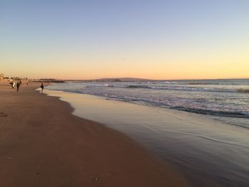 Scenic view of beach against clear sky during sunset