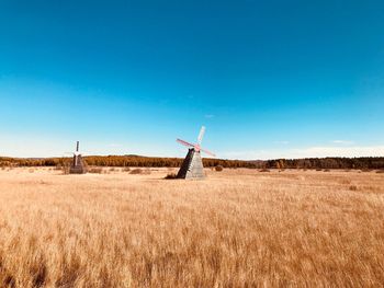 Traditional windmills on field against clear blue sky