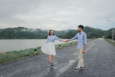 Young couple standing on mountain against sky