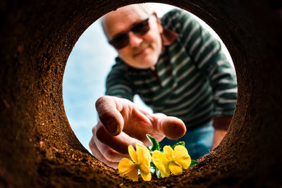 Midsection of man holding yellow flowering plant