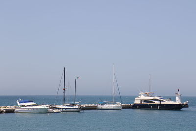 Sailboats in sea against clear sky