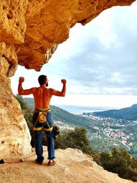 Rear view of shirtless man standing on rock