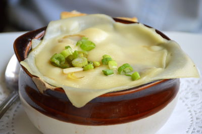 Close-up of onion soup with cheese served in container on table