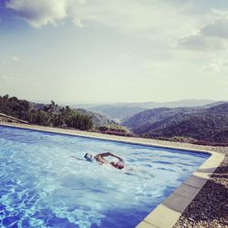 Man swimming in pool against sky