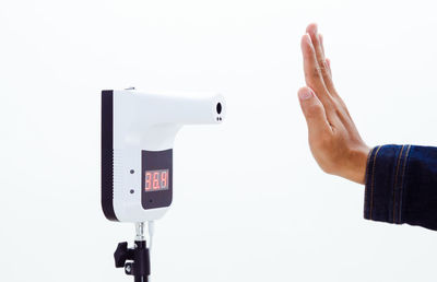 Close-up of hand photographing against white background