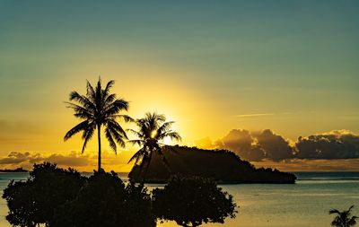 Silhouette palm trees on beach against sky at sunset