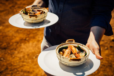 High angle view of person holding ice cream in plate on table