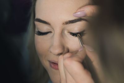 Cropped hand applying make-up to woman