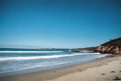 Scenic view of beach against clear blue sky