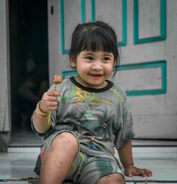 Cute smiling girl holding food against door