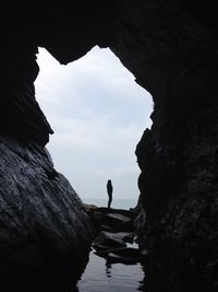 Silhouette man standing on cliff by sea against sky