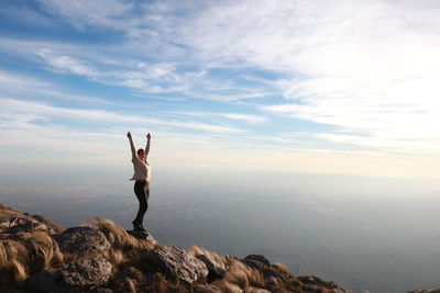 Woman with arms outstretched standing on mountain