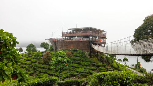 Built structure by trees and plants against sky