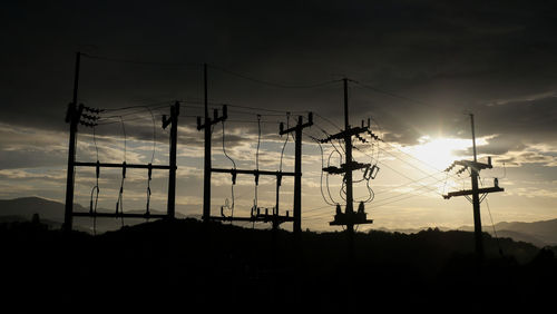Low angle view of silhouette electricity pylon against sky during sunset