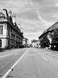 Road by buildings in city against sky