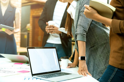 Midsection of business people standing at desk