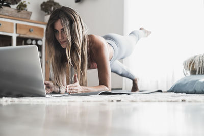 Young woman sitting on bed at home