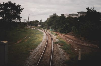 Railroad tracks by trees against sky