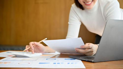 Midsection of woman using laptop on table