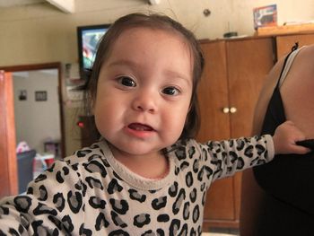 Portrait of cute girl standing by mother at home