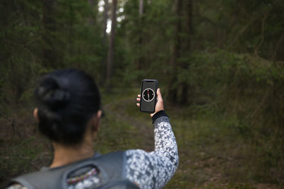 Woman using compass on smart phone while hiking