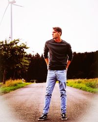 Full length of young man standing on road against sky