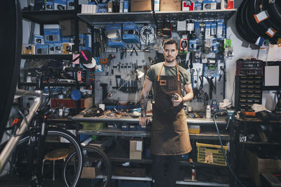 Portrait of man with bicycle standing against graffiti