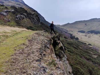 Man standing on rock against sky