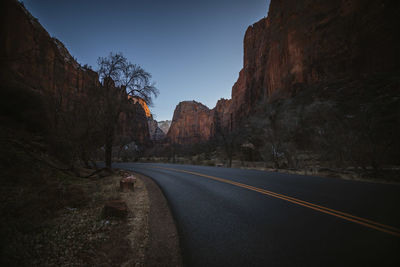 Road leading towards mountain against clear sky