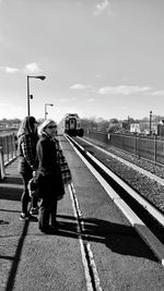 Man walking on railroad tracks against sky