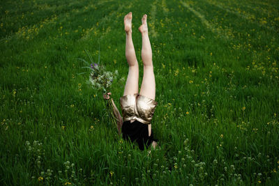 Woman doing headstand amidst plants on land