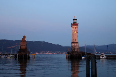 Lighthouse by sea against clear sky