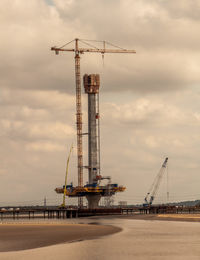 Cranes at construction site against sky