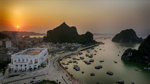 High angle view of buildings by sea against sky during sunset