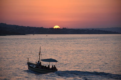 Scenic view of sea with boat  against sky during sunset